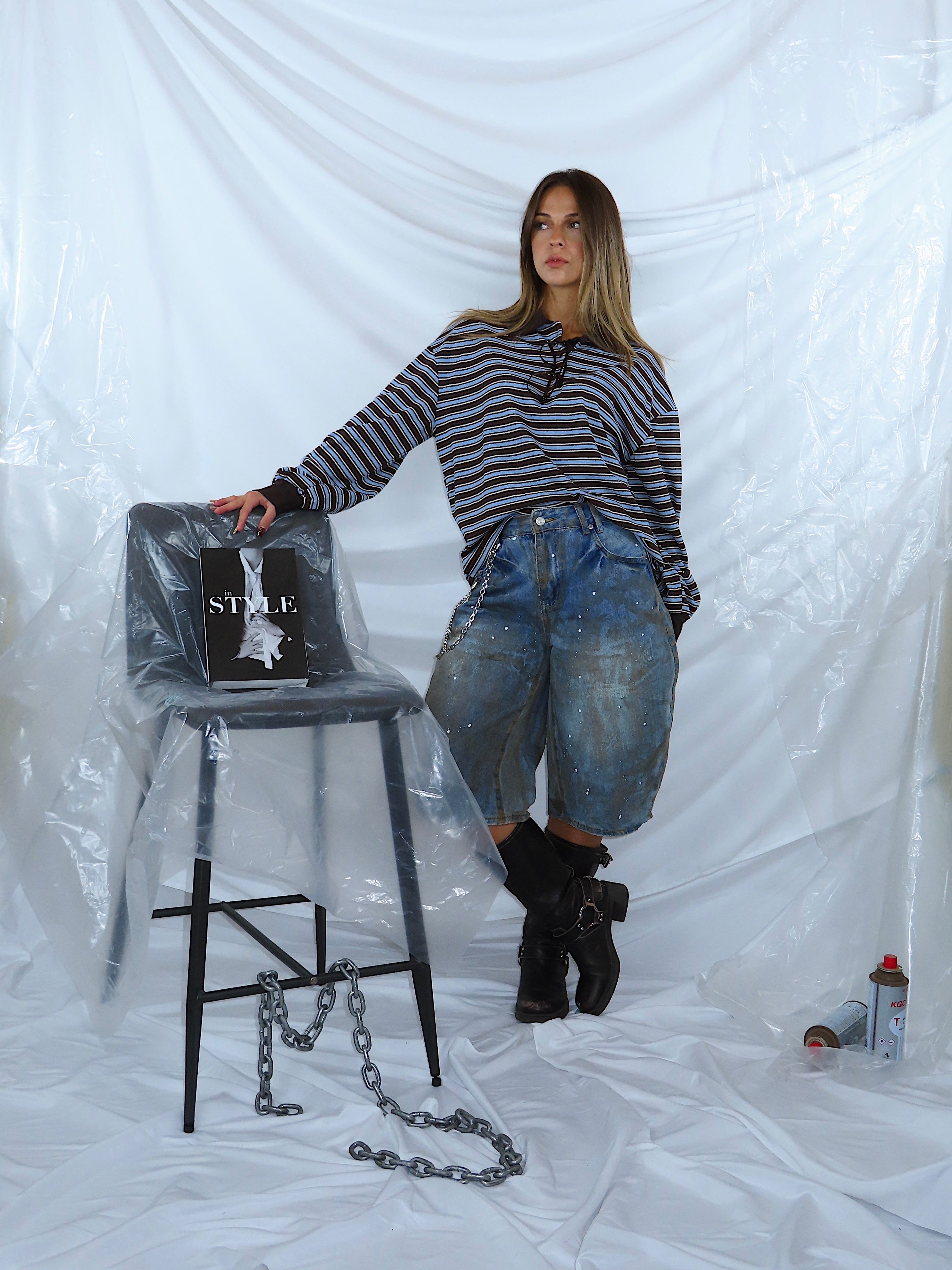 Look completo a figura intera: polo a righe marrone e celeste abbinata a bermuda in denim e stivali, outfit casual.