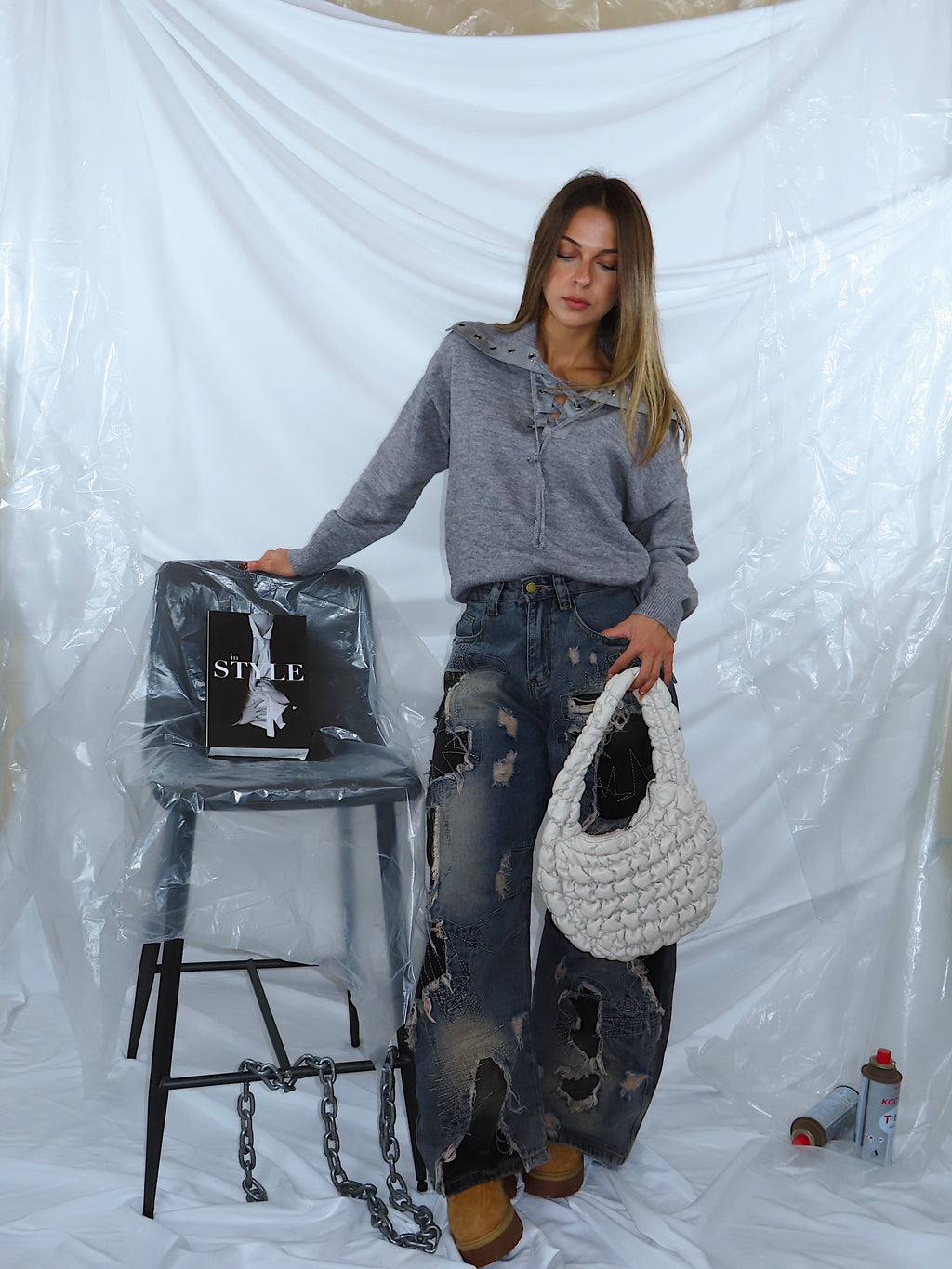 Look da donna con maglione grigio e jeans in denim blu, indossato da modella in piedi, vista frontale.