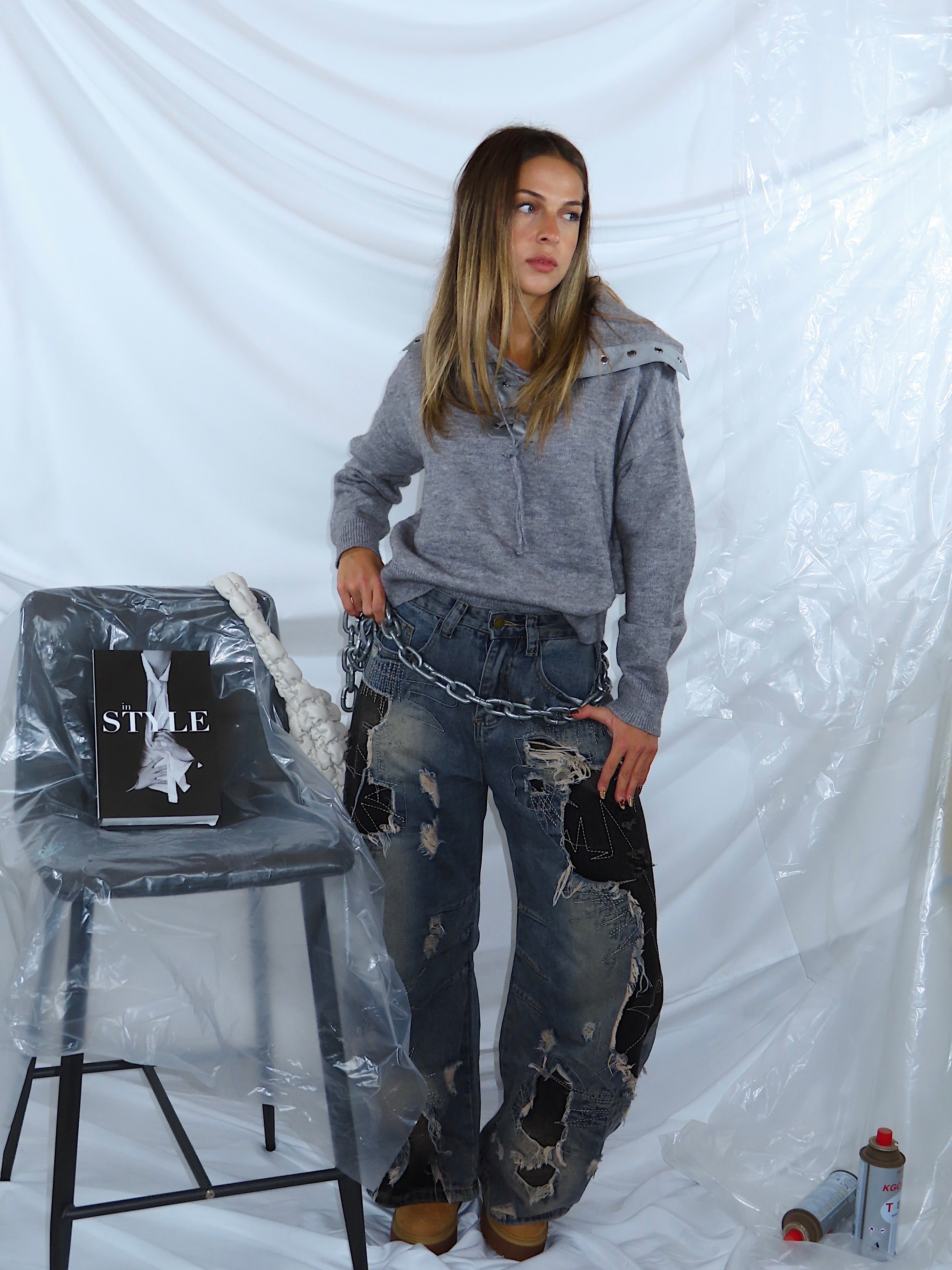 Outfit streetwear completo a figura intera con jeans in denim a lavaggio medio e maglione grigio, look casual urbano.