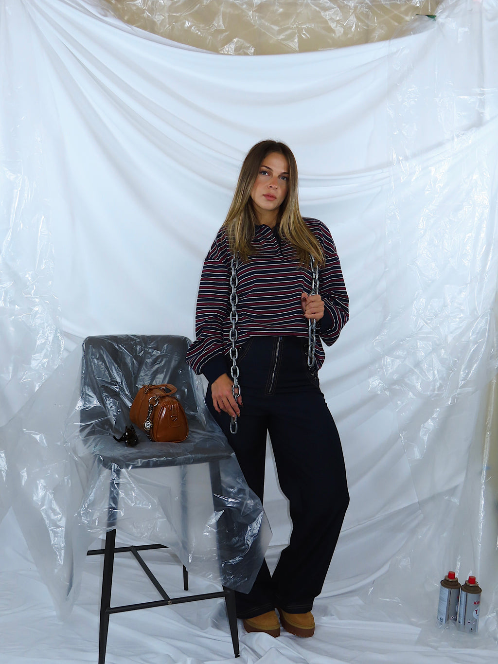 Figura intera frontale con outfit casual: polo a righe bordeaux e blu abbinata a jeans in denim blu scuro.